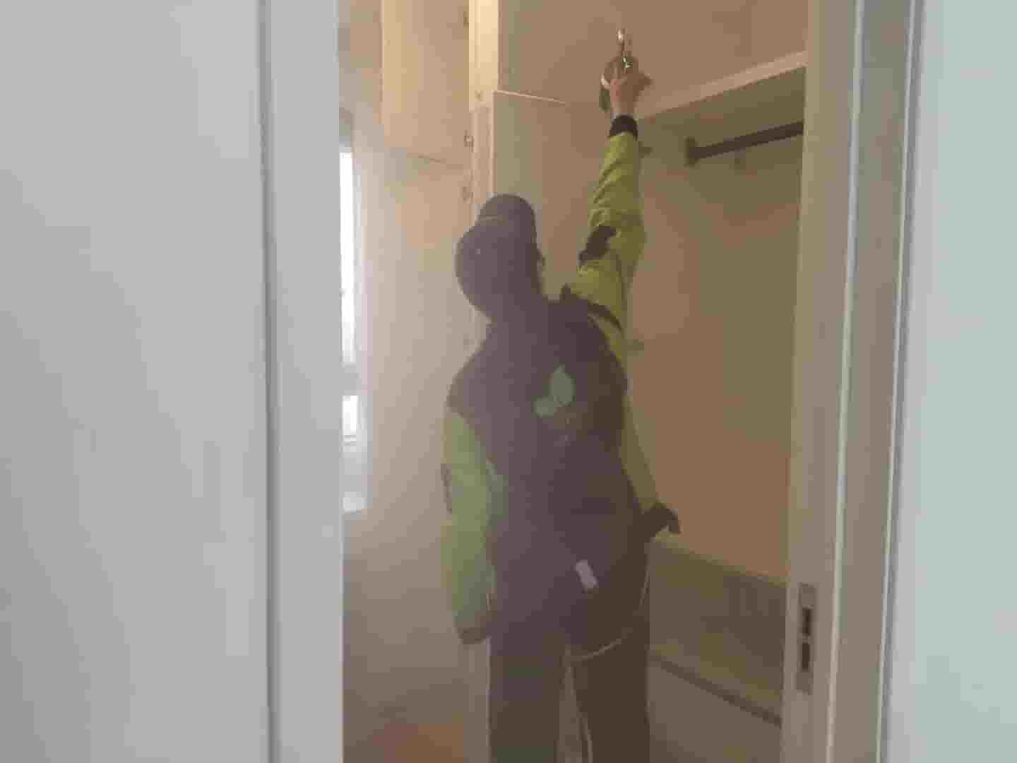 格瑞樂專業(yè)檢測人員，身著統(tǒng)一工作服，手持檢測工具箱，站在剛裝修完的新房門口，準(zhǔn)備開展甲醛檢測工作。